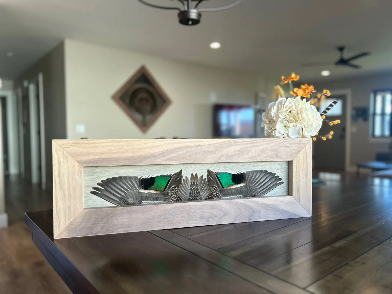 Green-winged teal feather board in a dining room with a turkey diamond mount behind it