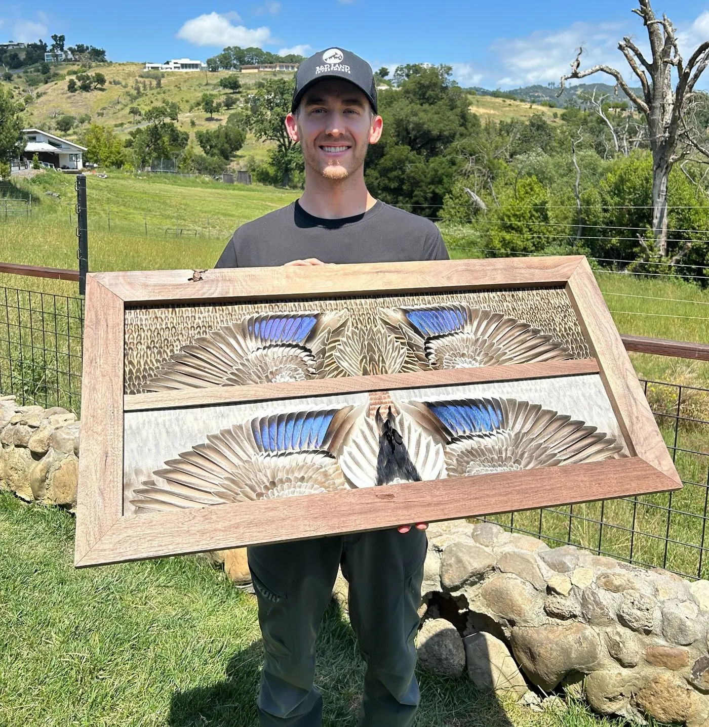 Jake Davidson smiling and holding a finished double white-winged mallard board outdoors