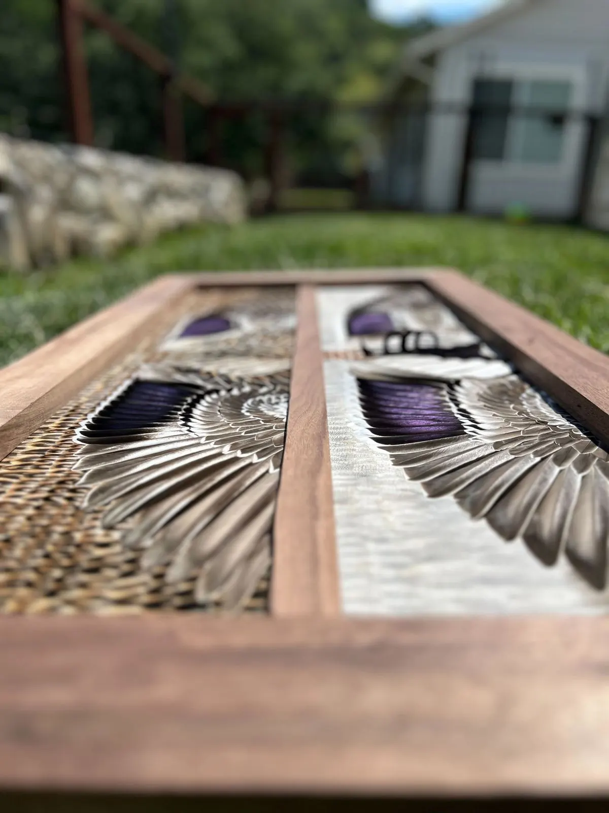 Close-up of hand-laid feathers along a hardwood frame edge